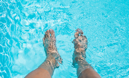 Male feet dipping in swimming pool Male feet dipping in swimming pool