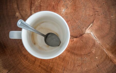 Coffee cup with coffee stain at bottom on wooden background