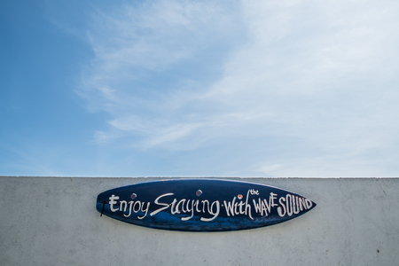 Surf board on white wall, and blue skyの写真素材