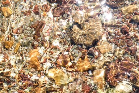 Transparent clear water on stones, with sunlight reflectionの写真素材