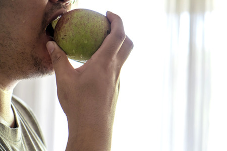 Close-up fat guy bitten an appleの写真素材