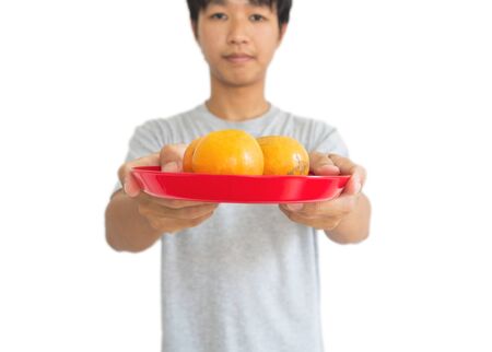 Asian guy holding oranges on tray, for offering an ancestor in Chinese new years, isolated on white backgroundの写真素材