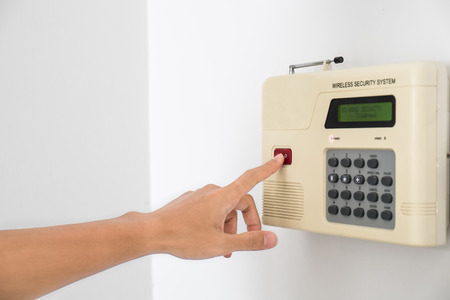 Home security system with hand pushing red buttonの写真素材