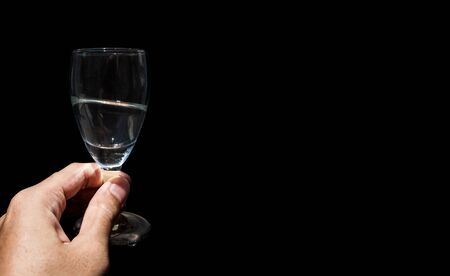 Hand holding wine glass with copy space, isolated on black backgroundの写真素材