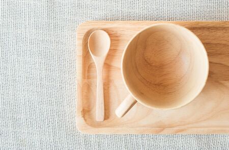 Wooden cup and spoon with saucer on grey textileの写真素材