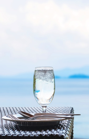 Glass of cold water on dining table with blue ocean backgroundの写真素材