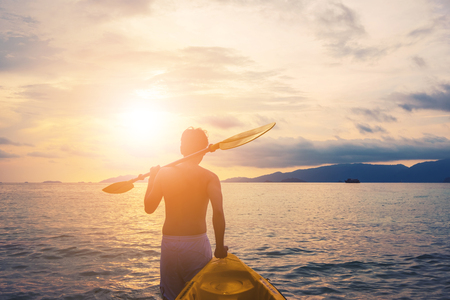 a guy pulling kayak to the sea in sunset, vacation holiday summertime concepts, vintage toneの写真素材