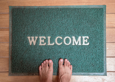 green foot scraper mat on wooden floor with barefoot standingの写真素材