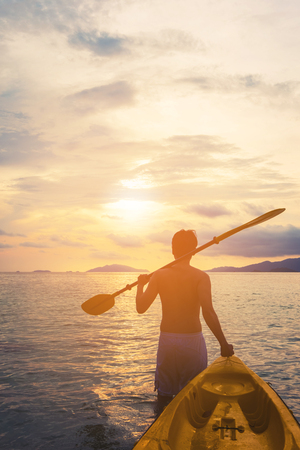 a guy pulling kayak to the sea in sunset, vacation holiday summertime concepts, vintage toneの写真素材