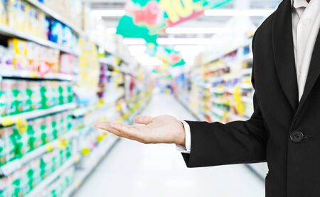 Businessman stretch hand with defocus supermarket aisle backgroundの写真素材