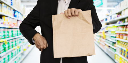 Businessman showing brown paper bag at supermarketの写真素材