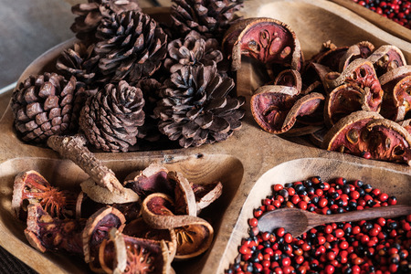 Dried pinecone with bale fruit on wooden tray, selective focus, shallow depth of fieldの写真素材