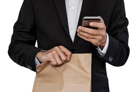 Businessman holding brown paper bag, and using smart phone, isolated on white backgroundの写真素材