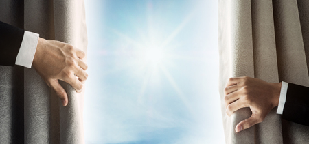 Businessman hand opening curtain, receiving bright light in the morningの写真素材