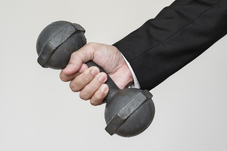 Businessman hand holding heavy dumbbellの写真素材