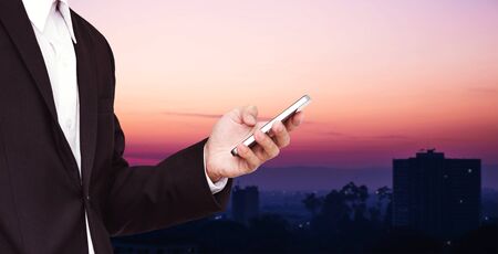 Businessman using smartphone with defocus city in dawnの写真素材