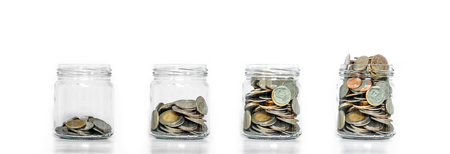 Money saving, glass jar arrange with coins inside growing, on white backgroundの写真素材
