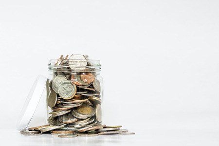Coins in glass jar, and covered, with copy space on white background