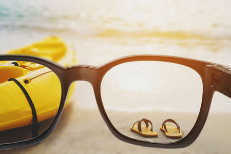 Sunglasses with yellow flip flop and kayak on the beach in sunset, vintage toneの写真素材
