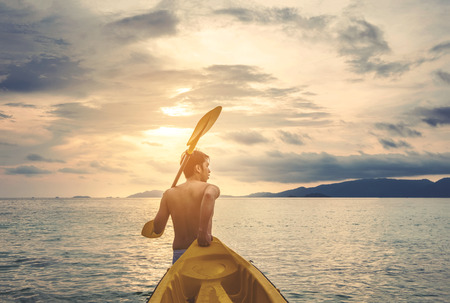 a guy pulling kayak to the sea in sunset, vacation holiday summertime concepts, vintage toneの写真素材