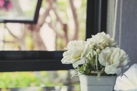 Close-up white fake roses flower with cobweb, near the window, selective focus, vintage toneの写真素材