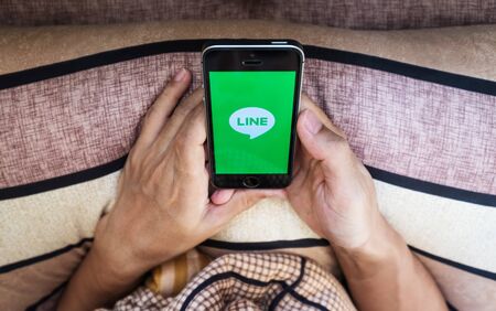 THAILAND - 8 AUG - Asian guy hand using Line application on Apple iphone IOS system smartphone, on bed in the morningのeditorial素材