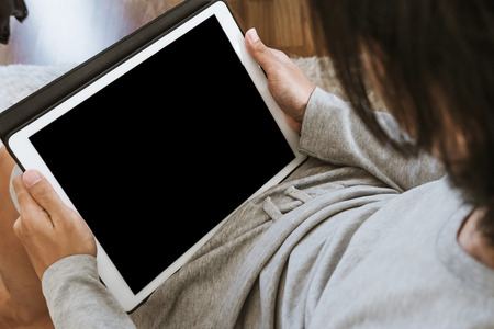 Asian guy using digital tablet in living room, copy space on screen