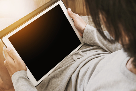 Asian guy using digital tablet in living room, copy space on screen, and bright sunlight, vintage toneの写真素材