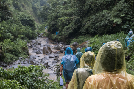 People in raincoat walking in hill in rainy day, selective focus