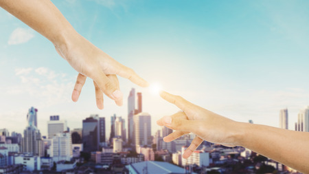 Hand reaching finger together with shine bright light, and Bangkok cityscape background