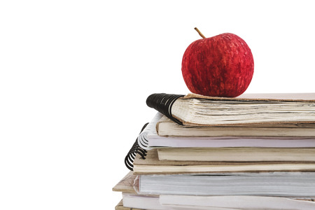Close-up red apple on stacked of old used notebooks, isolated on white background with copy spaceの写真素材