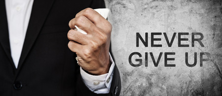 Businessman fist squeeze paper on concrete texture with NEVER GIVE UP word, panorama composition