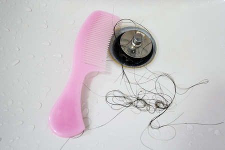 Hair loss after taking shower in washbasin with pink combの写真素材