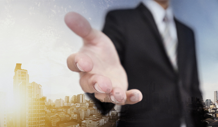 Businessman extending hand with panoramic cityscape of Bangkok city in sunrise, helping handの写真素材