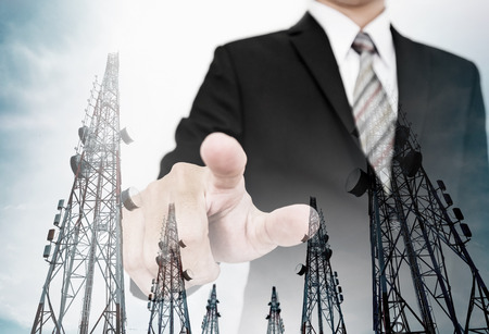 Businessman pointing finer to screen with double exposure telecommunication electronic towers, business networkの写真素材