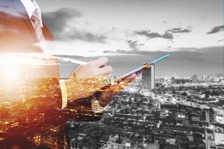Double Exposure Businessman Working on Digital Tablet Outdoor, and city view backgroundの写真素材