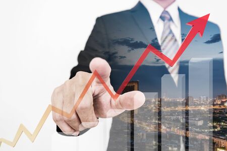 Businessman drawing a rising up arrow by finger, representing business growthの写真素材