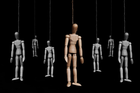 Group of wooden marionettes puppet hangman by rope, on black backgroundの写真素材