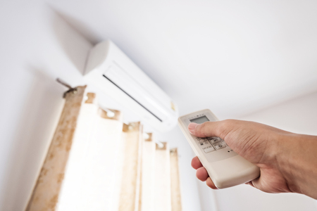 Hand using remote control air conditioning, representing energy saving conceptsの写真素材