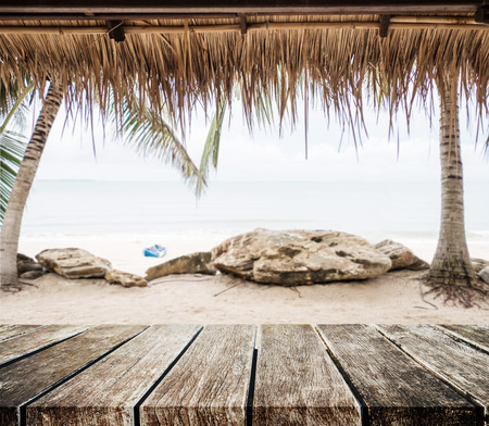 The beach, wooden tabletop with straw roof at tropical beach. Holiday beach travelの写真素材