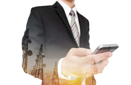 Businessman using smart phone with double exposure panoramic cityscape and telecommunication towers in sunrise, isolated on white backgroundの写真素材