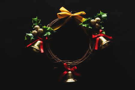 Christmas decoration, Wreath woven from the branch of the vine with golden bells and green leaf, on black background, low key imagesの写真素材