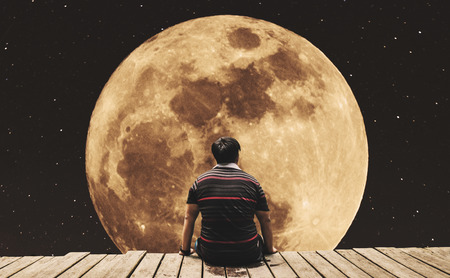 Silhouette a man sitting relaxing under full moon at night with stars on the skyの写真素材