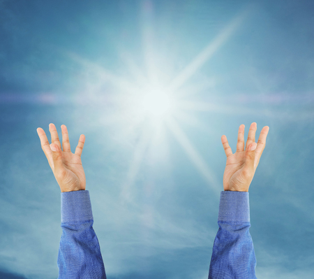 Hand trying to reach on the sky with sunshine raysの写真素材