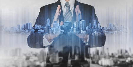 Double exposure businessman holding blue city hologram, real estate business technologyの写真素材