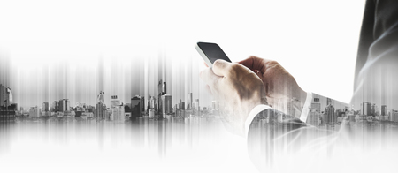 Double exposure businessman using smart phone, with city backgroundsの写真素材