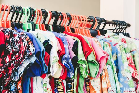 Colorful child clothes hang on rack in storeの写真素材