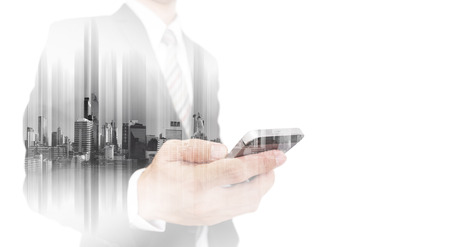 Double exposure businessman using smart phone, with city backgroundsの写真素材