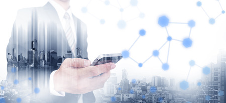 Double exposure businessman using smartphone with modern city, network communication technology...