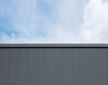 Corrugated factory industry wall on blue sky with cloudsの写真素材